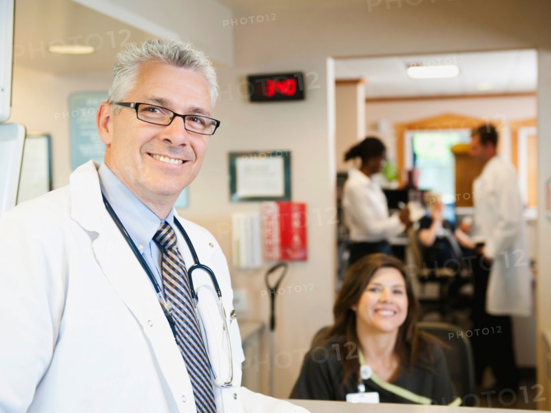 Portrait of confident doctor with female nurse in background.