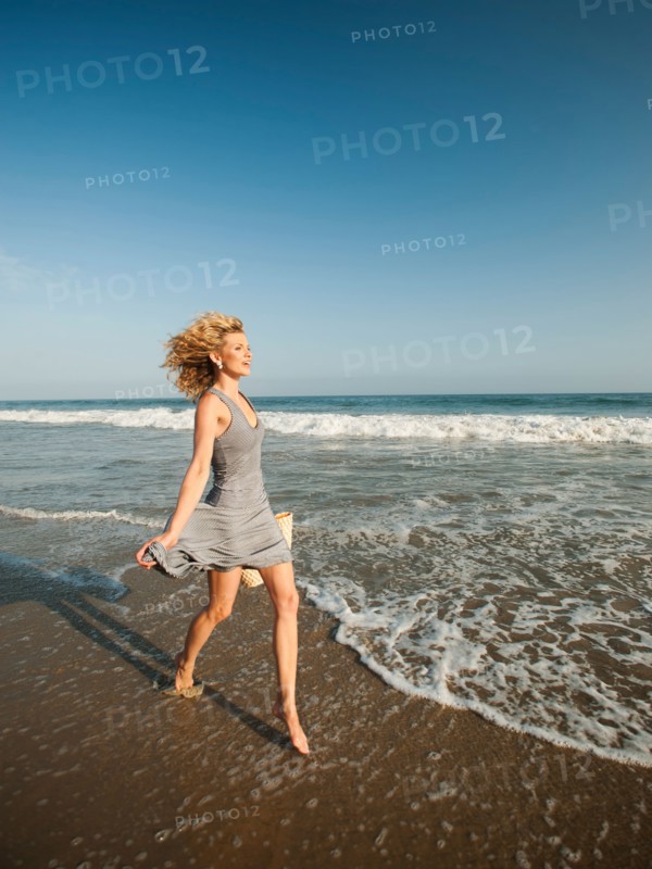 Attractive young woman walking on sandy beach.