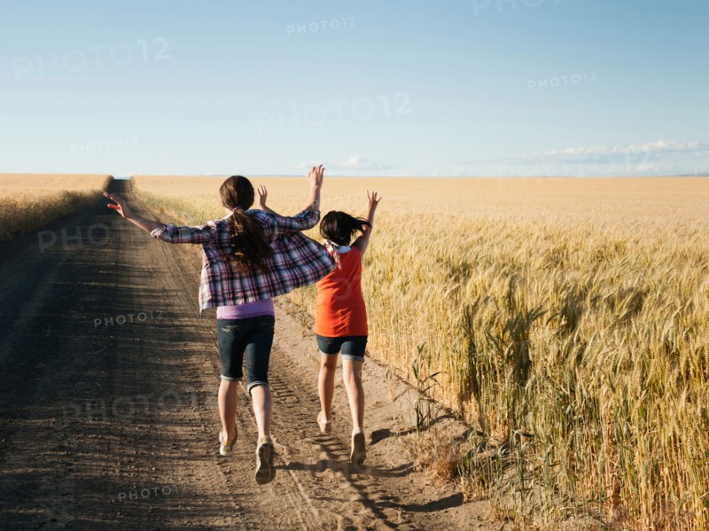 Girls (12-13, 10-11) running along dirt road.