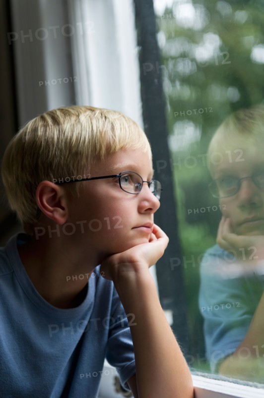 Boy (10-11) looking through window.