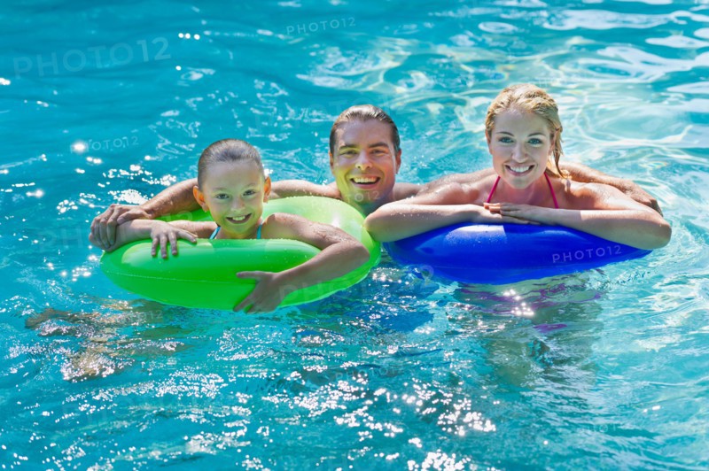Girl (10-11) with parents in swimming pool.