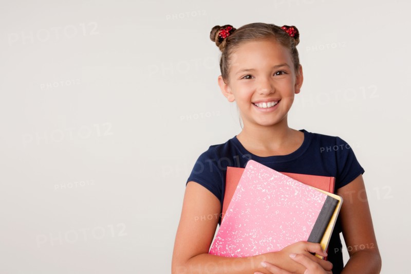 Studio portrait of girl (8-9) holding books. Photo: Rob Lewine