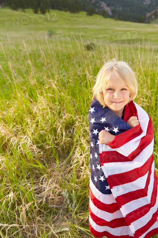 Portrait of boy (6-7) wrapped in American flag. Photo: Shawn O'Connor