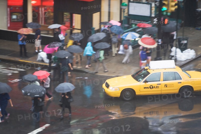 USA, New York State, New York City, Manhattan, Yellow taxi cab on street, pedestrians walking with umbrellas. Photo: fotog