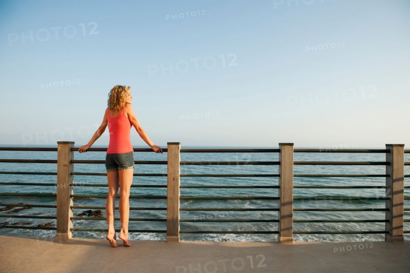 Young attractive woman contemplating seascape from terrace.