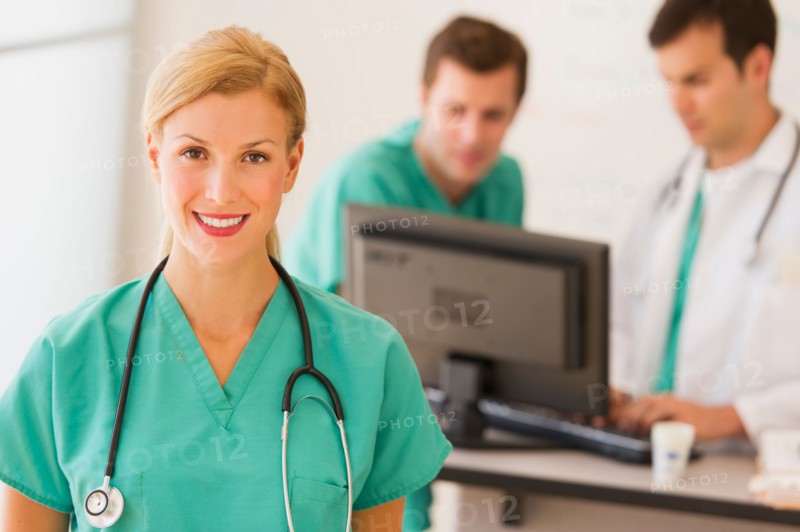 Portrait of female doctor in front of nurse's station.