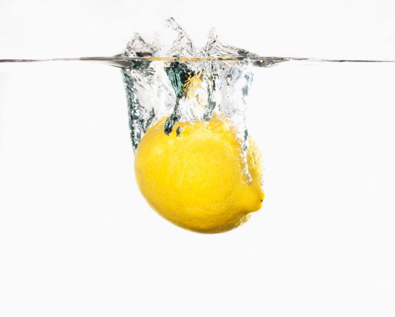 Studio shot of lemon splashing into water.