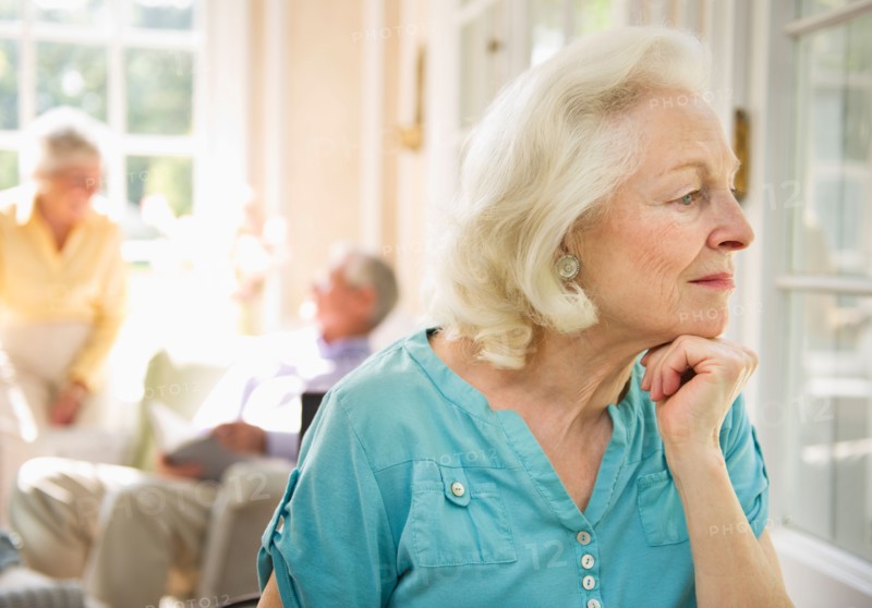 Senior woman looking through window in nursing home.