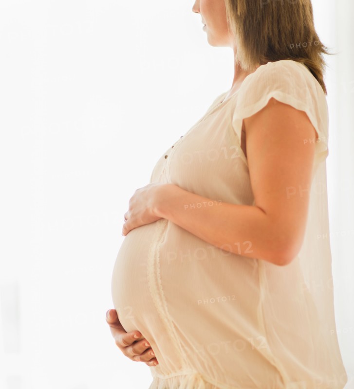 Pregnant woman looking through window.