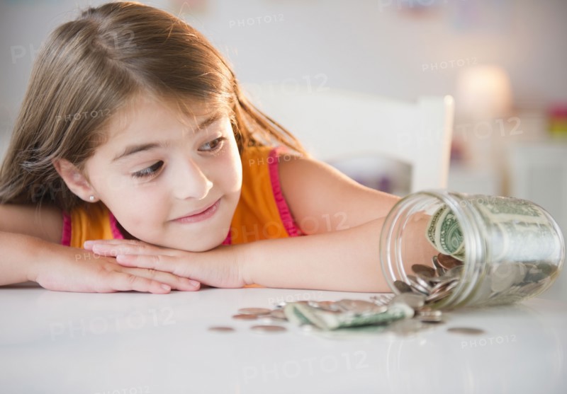 Girl ( 6-7) looking at savings in jar. Photo : Jamie Grill