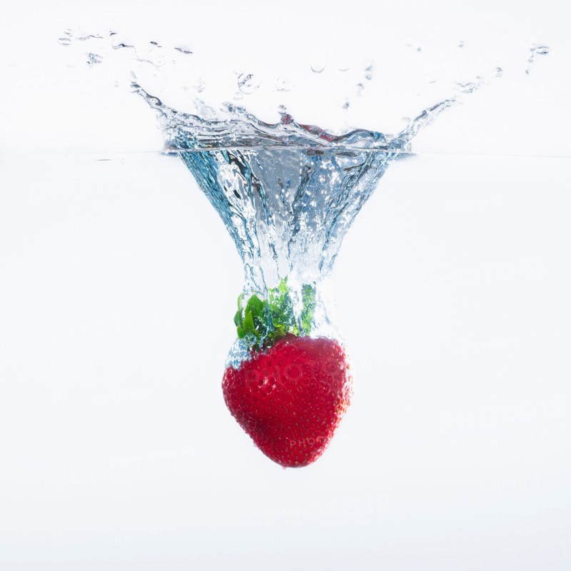 Strawberry splashing into water, studio shot. Photo : Daniel Grill