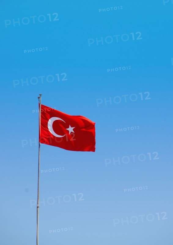 Turkey, Turkish flag against blue sky. Photo : Tetra Images