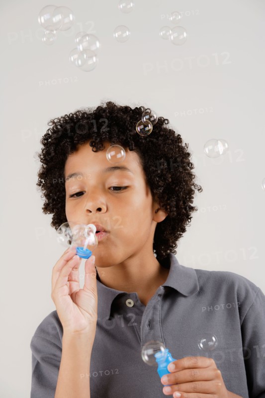 Studio portrait of boy (8-9) blowing bubbles. Photo : Rob Lewine