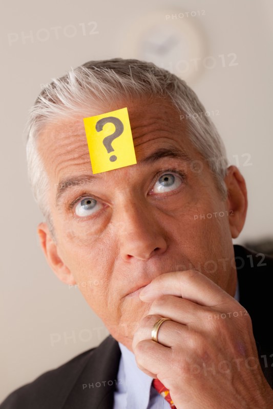 Studio portrait of senior businessman with adhesive note on forehead. Photo: Rob Lewine