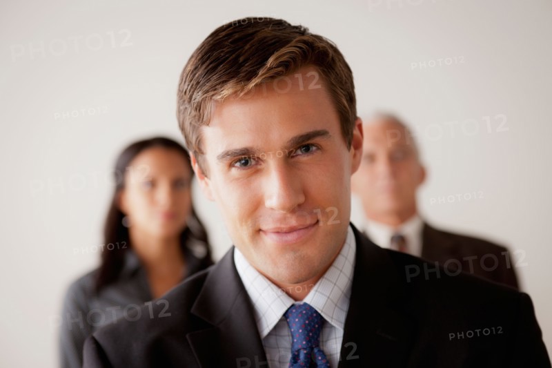 Studio shot of business people, focus on young business man. Photo : Rob Lewine