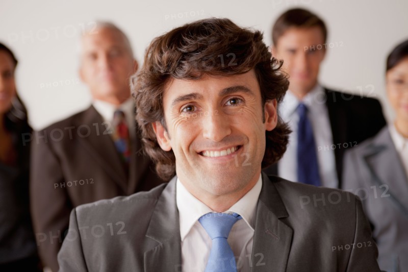 Studio shot of business people, focus on mid adult business man. Photo : Rob Lewine