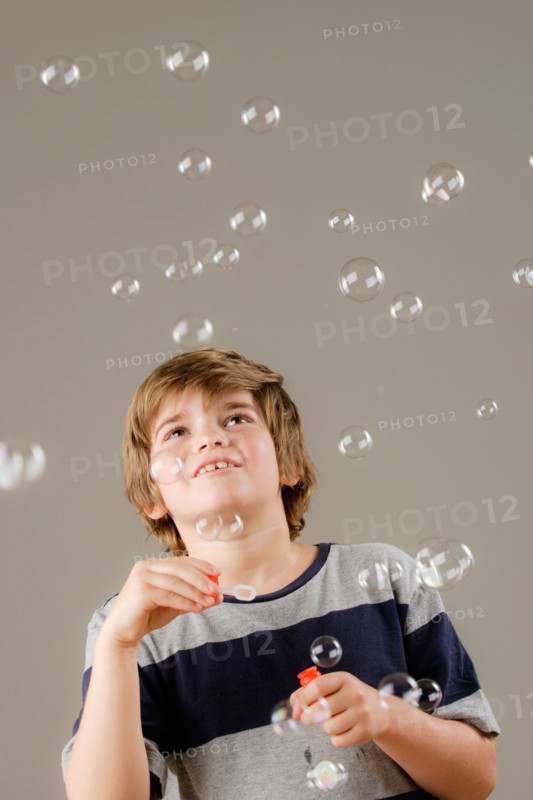 Studio shot of boy (8-9) blowing bubbles. Photo : Rob Lewine
