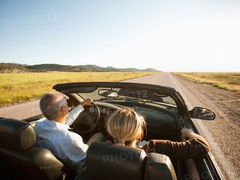 USA, Utah, Kanosh, Mad-adult couple driving through desert plains in convertible car. Photo: Erik Isakson