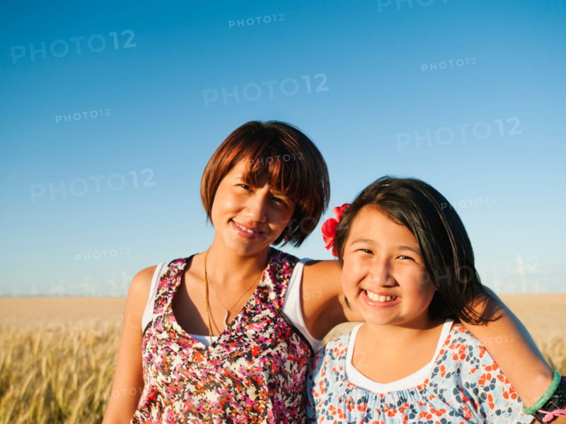 Mother and daughter (10-11) standing in wheat field .