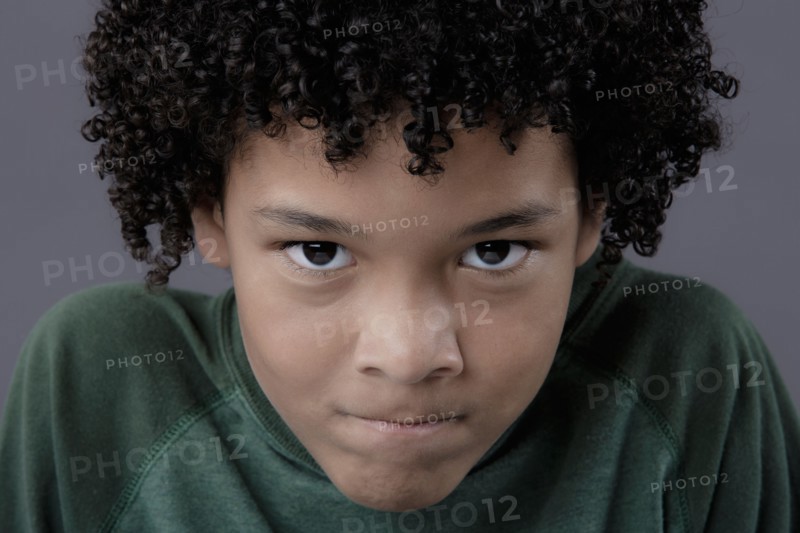 Portrait of boy (8-9) looking angry, studio shot. Photo : Rob Lewine