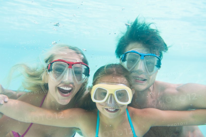 Parents with daughter (10-11) swimming underwater. Photo: Daniel Grill