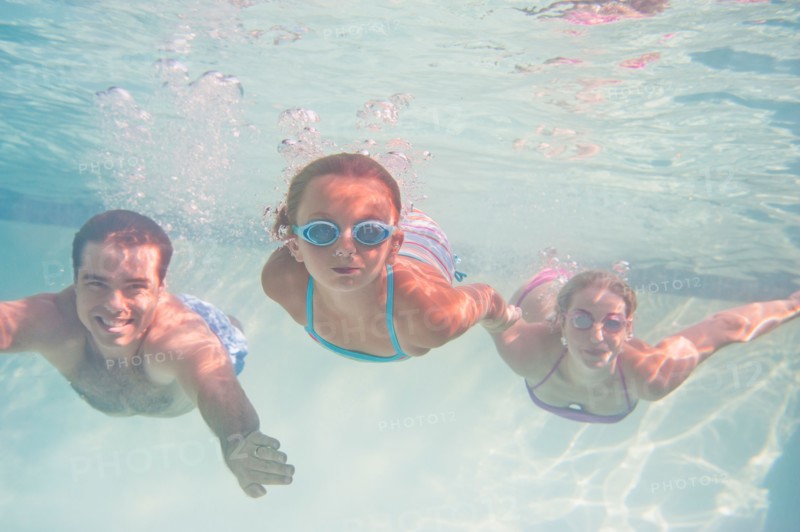 Parents with daughter (10-11) swimming underwater. Photo : Daniel Grill