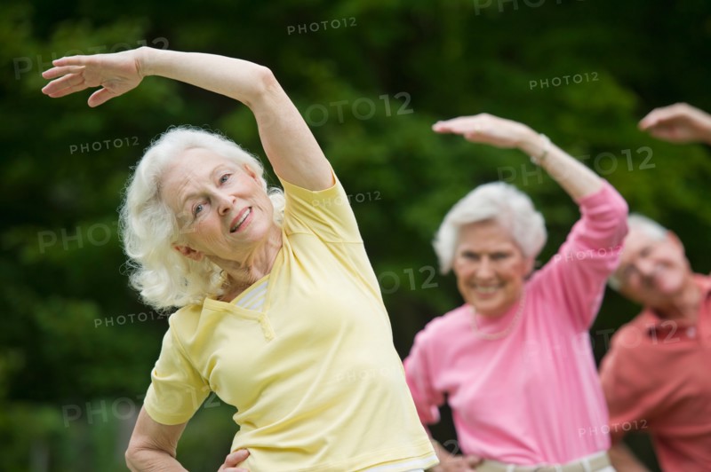 Seniors stretching in park.