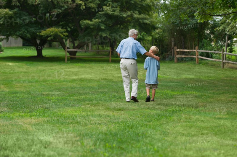 Grandfather and grandson (10-11) walking in park.