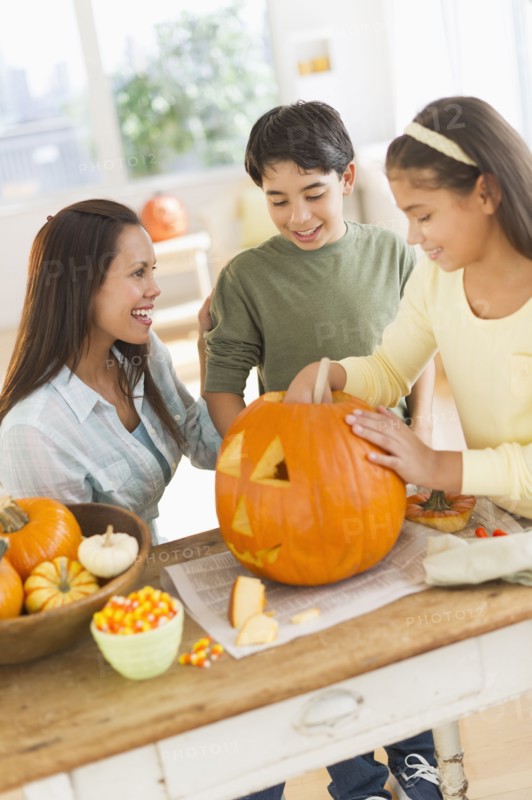 Mother with son (12-13) and daughter (10-11) doing Jack o lantern.
