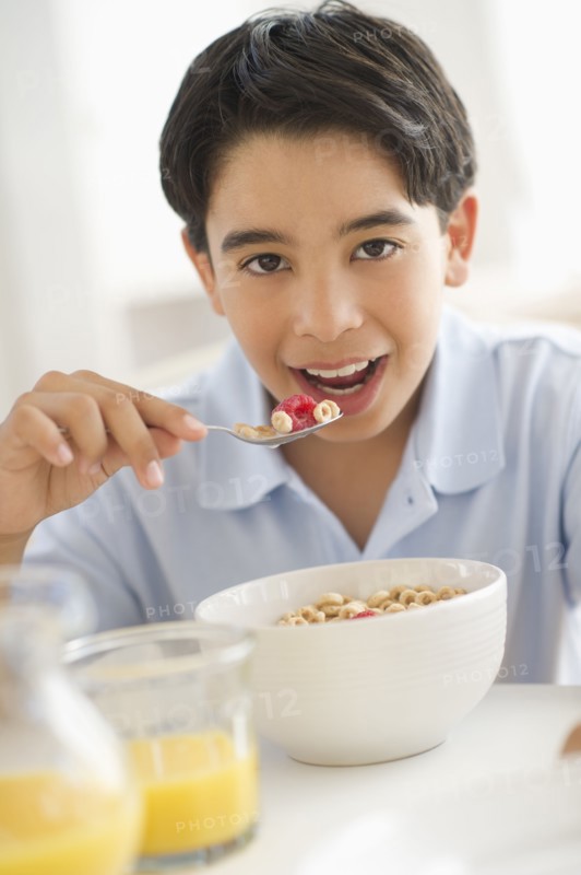 Boy (12-13) having cereals for breakfast.