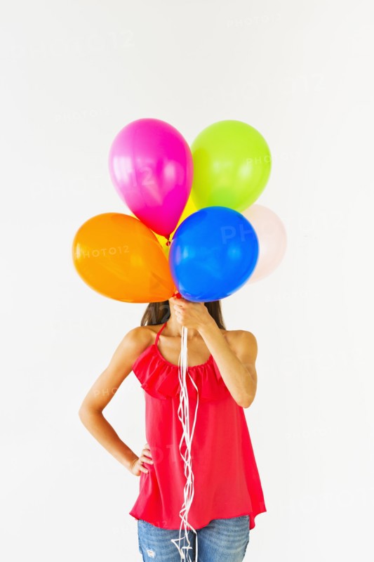 Smiling woman holding balloons, studio shot.