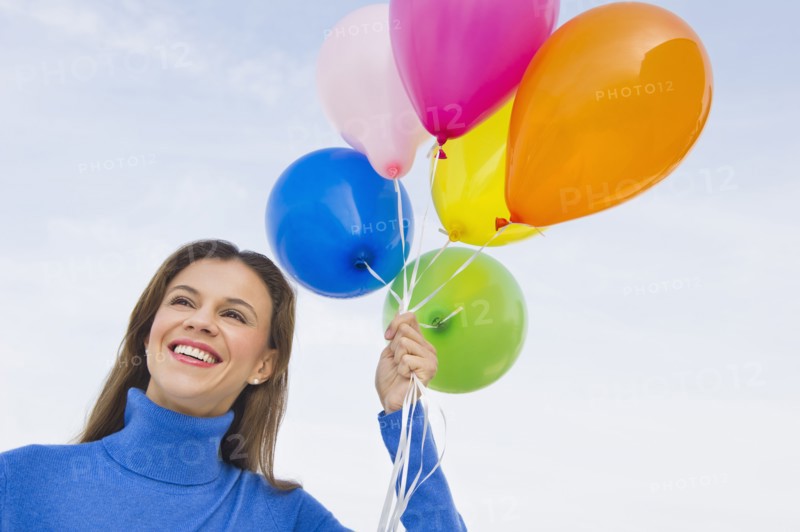 Smiling woman holding balloons.
