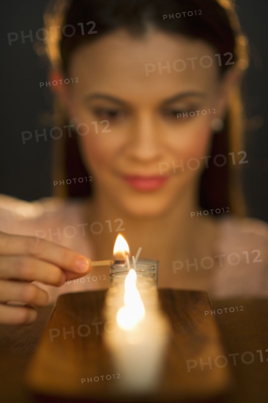 Woman igniting candle.