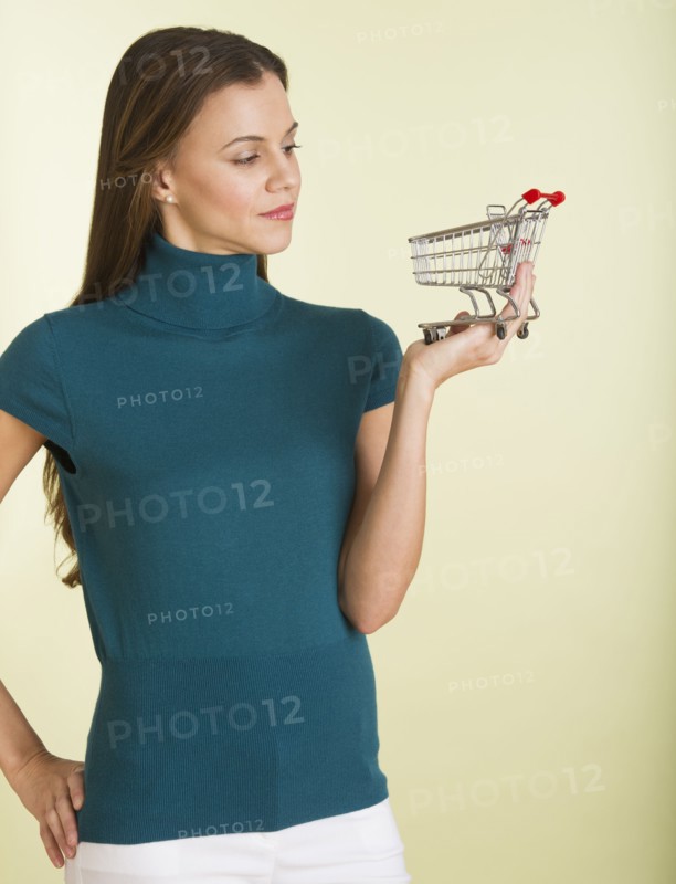 Studio shot of woman holding small shopping cart.