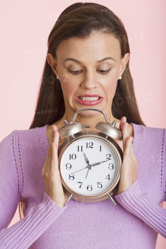 Studio shot of woman holding alarm clock.