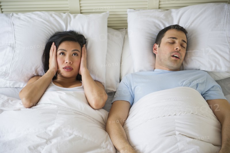 Couple in bed, man snoring.