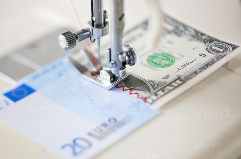 Halves of banknotes being sewed with sewing machine.