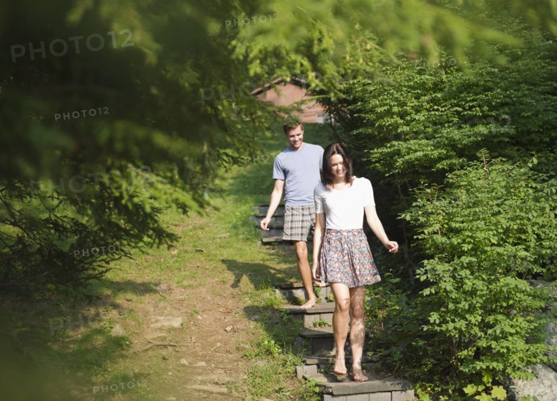 USA, New York, Putnam Valley, Roaring Brook Lake, Couple walking down steps among trees. Photo: Jamie Grill