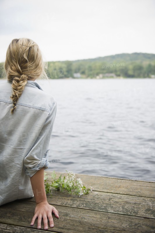 USA, New York, Putnam Valley, Roaring Brook Lake, Rear view of woman sitting on pier by lake. Photo: Jamie Grill