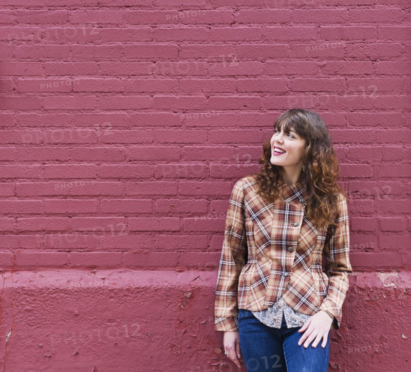 Woman leaning against purple brick wall. Photo: Daniel Grill