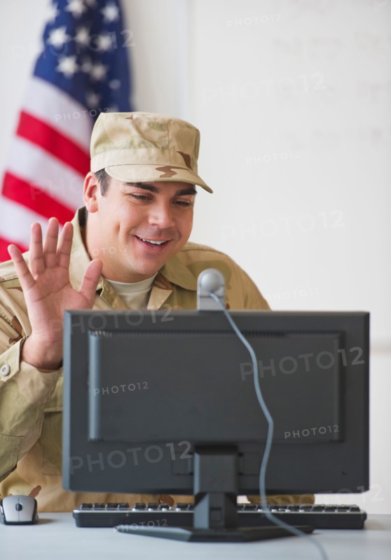 Man wearing military uniform waving to monitor. Photo: Daniel Grill