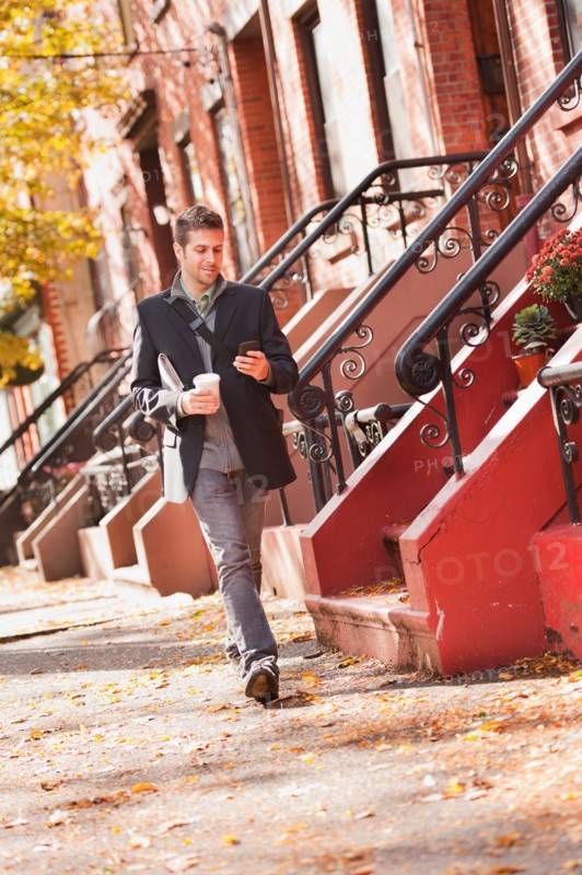 Man walking with mobile phone and coffee. Photo: Daniel Grill