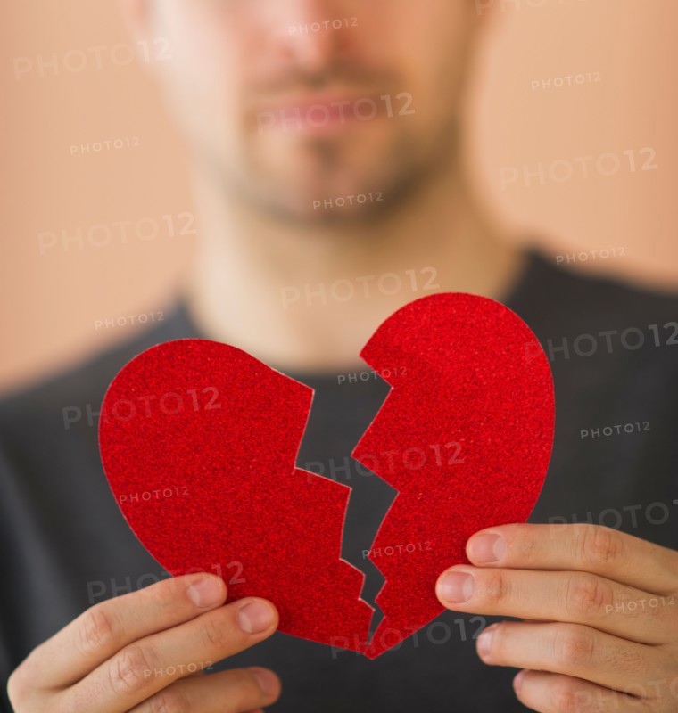 Young man holding broken paper heart. Photo: Daniel Grill