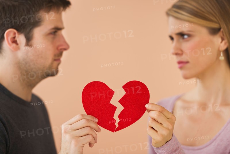 Couple holding red broken paper heart. Photo : Daniel Grill
