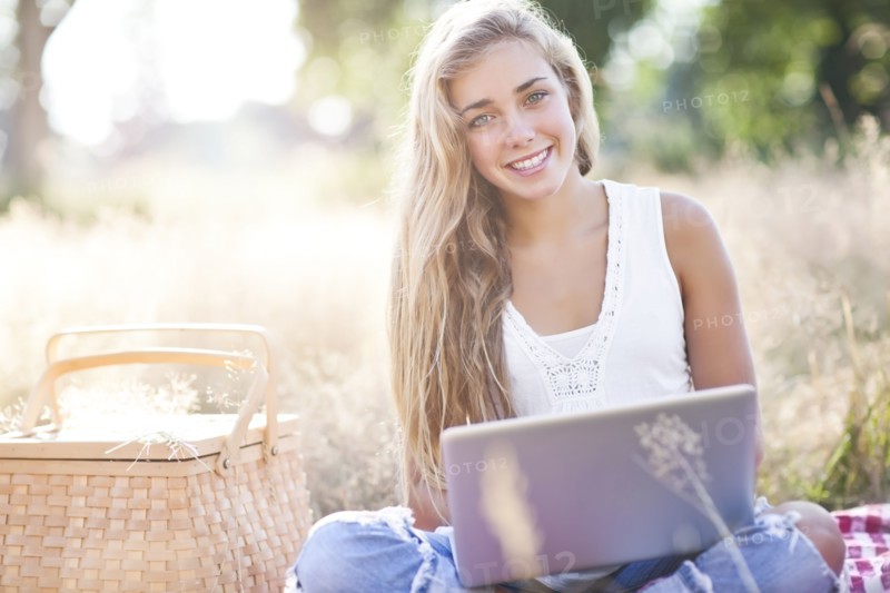 Teenage girl (16-17) posing with laptop outdoors. Photo : Take A Pix Media