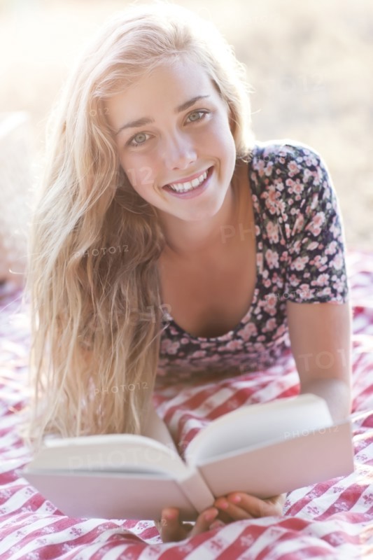 Happy teenage girl (16-17) reading book outdoors. Photo: Take A Pix Media
