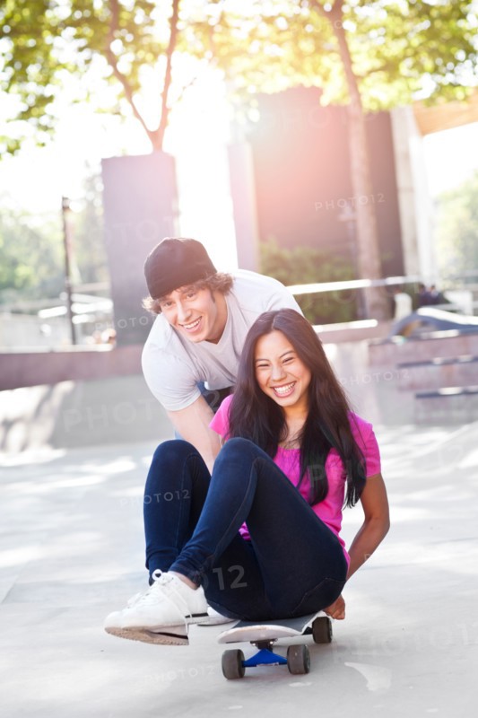 Young multi-racial couple playing with skateboard. Photo: Take A Pix Media