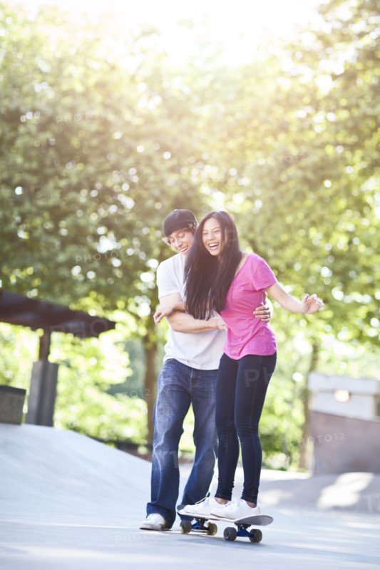 Young multi racial couple skateboarding. Photo : Take A Pix Media