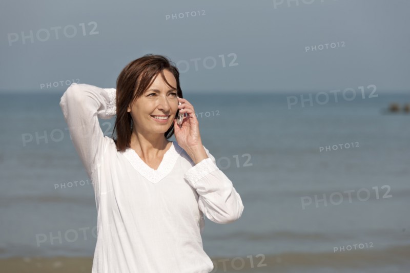 Woman on beach talking on phone. Photo : Jan Scherders