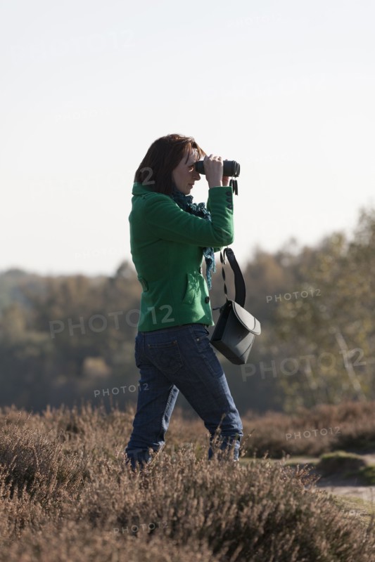 The Netherlands, Veluwezoom, Posbank, Woman in countryside looking through binoculars. Photo : Jan Scherders
